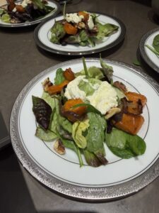 Spinach and roasted squash salad with soft cheese and walnuts, served on platinum-rimmed china