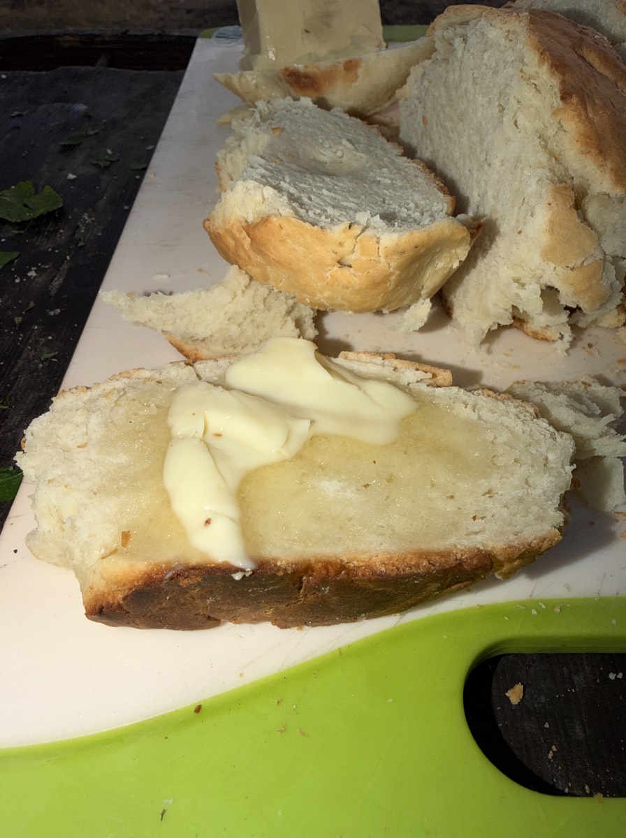 A slice of campfire bread with butter melting on top